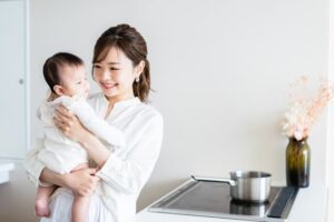 キッチンで赤ちゃんを抱っこしている女性