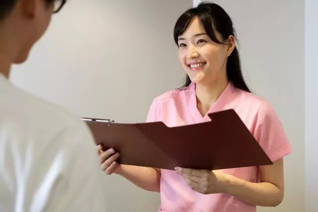 カルテを見ながら患者に確認している外来クラークの女性
