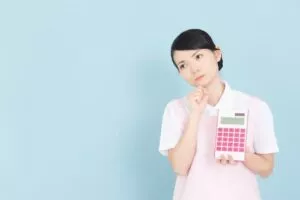 電卓を持って考えている介護職の女性