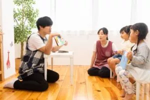 子どもに絵本を見せている保育士の男性