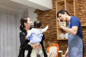 子どもとその保護者を見送る保育士の男性