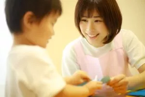 折り紙を教えている保育士女性