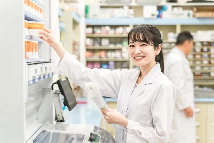 薬を手に取る調剤薬局で働く女性