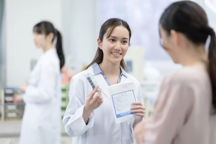 薬の説明をする医療事務スタッフの女性