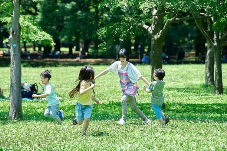 屋外で子どもと遊ぶ女性保育士