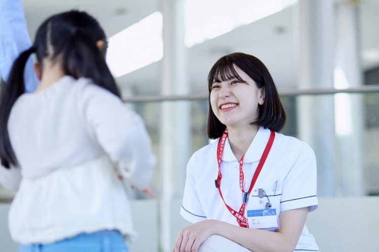 病院で子どもと会話する准看護師の女性